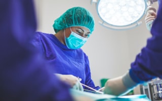 chirurg se zelenou pokrývkou hlavy v modrém plášti